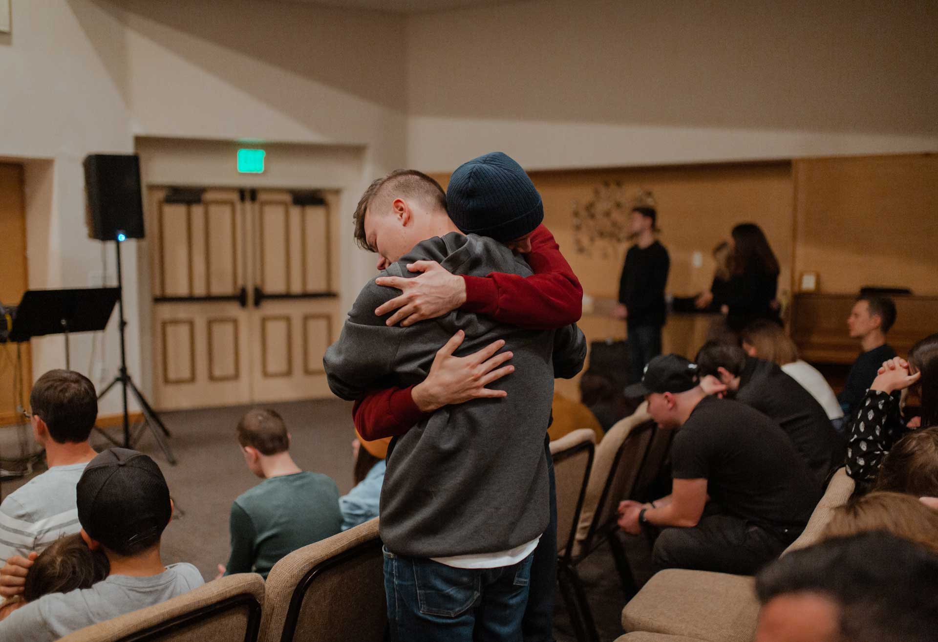 CHRISTIAN MEN IN CHURCH HUGGING WEARING BEANIE